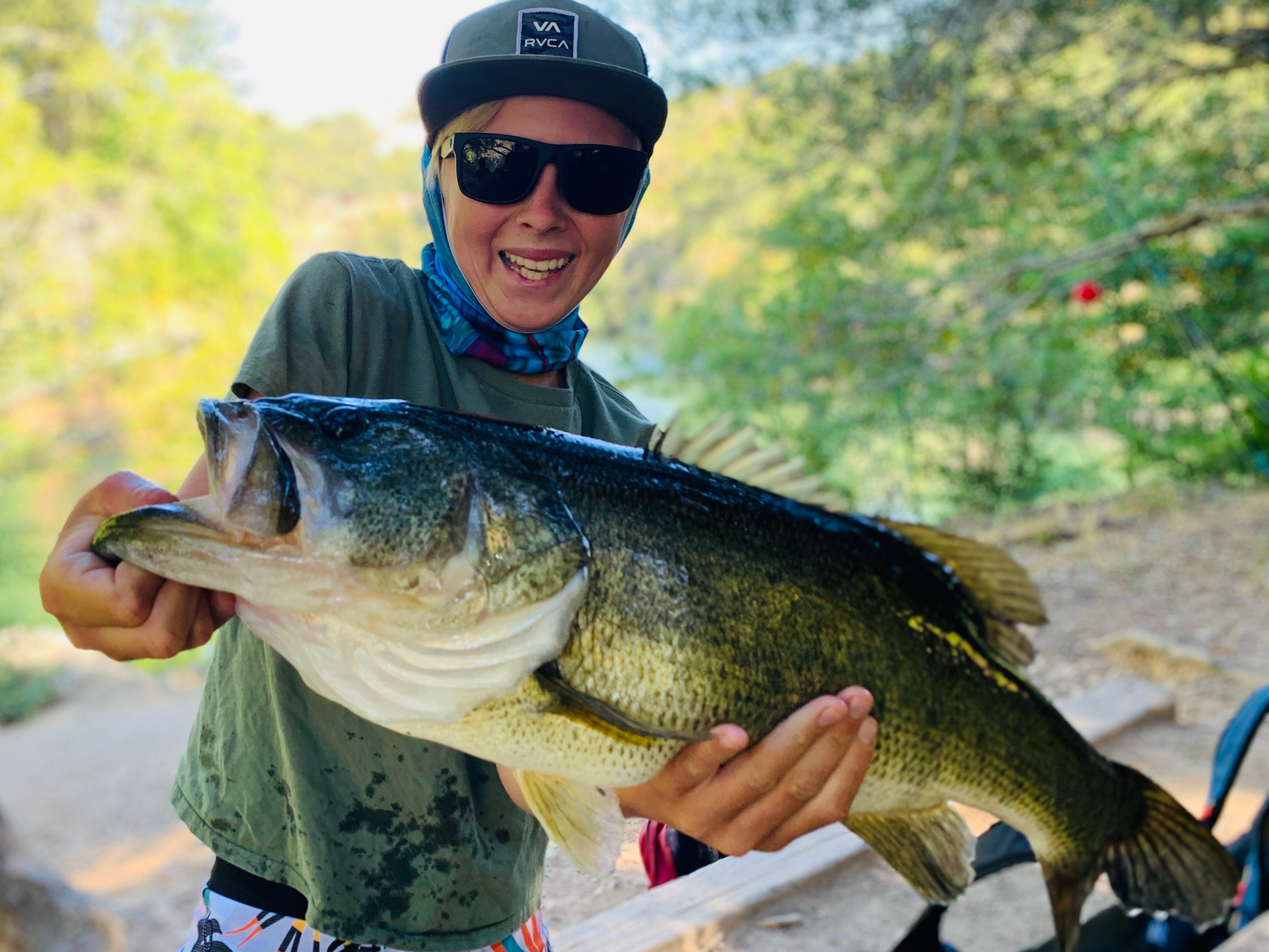 Person holding a large fish outdoors with greenery in the background