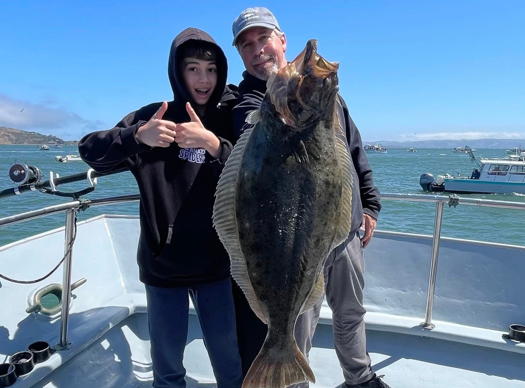 Two people on a boat holding a large fish with a scenic background